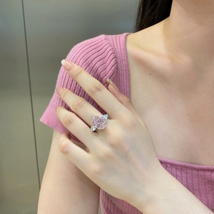 Gros plan détaillé d'une bague en cristal rose poire avec pierres latérales sur la main