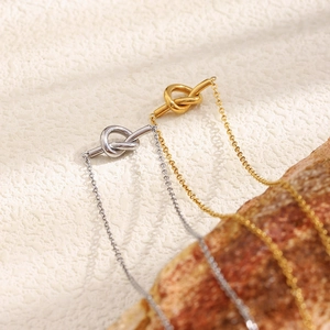 Detail of gold and silver knot T-bar necklaces on natural wood bark background
