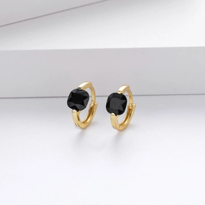 Detail of gold huggie hoop earrings with square black zircon stones on a white background