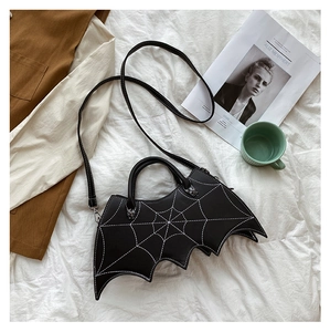 Detail of bat-shaped black PU leather handbag with white stitching and spider ornament