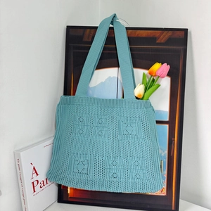 Detail of light blue knit tote bag with heart pattern and soft woven texture details