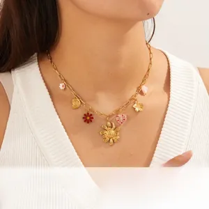 Detail of gold plated multi-pendant necklace with enamel floral and heart charms