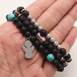 Lava stone and turquoise beaded bracelet featuring a silver angel pendant on wrist