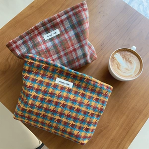 Plaid and houndstooth fabric makeup bags with zippers on a rustic wooden table