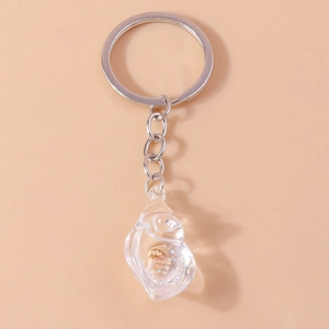 Glow-in-the-dark conch keychain with real seashell and silver chain on pink background