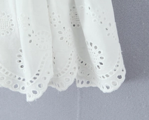 Detailopname van witte katoenen rok met delicaat opengewerkt borduursel en lagen