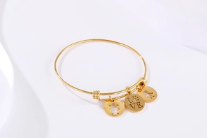 Detailed shot of golden adjustable bracelet with LOVE and figure pendants on white silk
