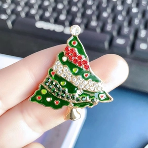 Detail of Christmas tree brooch with green enamel, red rhinestones and gold finish