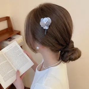 Barrette fleur grise en résine avec perle blanche sur les cheveux latéraux d'un mannequin