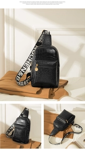 Detail view of black crocodile pattern chest bag with golden zipper and wide logo strap