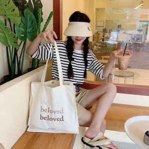 Détail de la broderie beloved sur un sac cabas en toile crème avec fermeture à pression