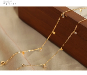 Detail of gold titanium necklace featuring zircon square pendants on silk fabric