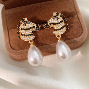 Dettaglio di orecchini a zebra vintage con cristalli scintillanti e perla bianca
