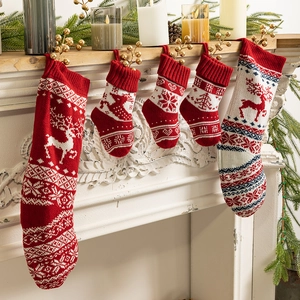 Knitted red and cream Christmas stockings with reindeer and snowflake patterns on fireplace