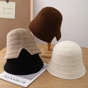 Winter chunky knit bucket hats in brown, beige, black and white displayed on a wooden table