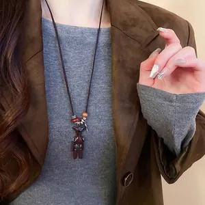 Cute abstract bear pendant necklace on long cord for women wearing a brown suit
