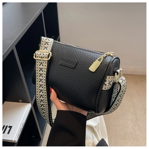 Detailansicht der schwarzen Zylindertasche aus Leder mit breitem geometrischem Gurt