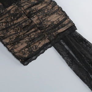 Dettaglio ravvicinato di pizzo nero e tessuto a rete con fodera beige sul vestito