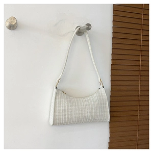 Détail du tissu tissé à carreaux blanc et de la fine bandoulière du sac sous l'aisselle
