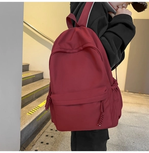 Seitenansicht des dunkelroten Rucksacks mit großem Fassungsvermögen an einem Model