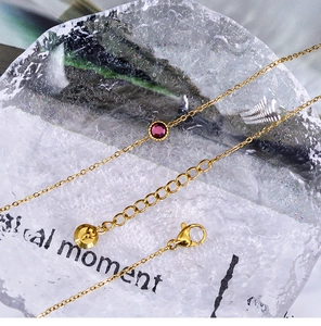 Detail of 18K gold-plated necklace featuring a purple round gemstone and lobster clasp