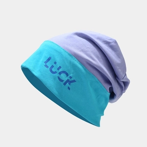 Detail of color-block knit beanie showing blue LUCK letter print on teal and purple fabric