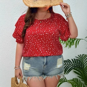 Detail view of a red polka dot puff sleeve top paired with distressed denim shorts and summer hat