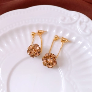 Macro shot of vintage gold earrings with champagne crystals on a white ceramic tray
