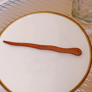 Macro view of wave-shaped wooden hair stick with brown finish and smooth texture