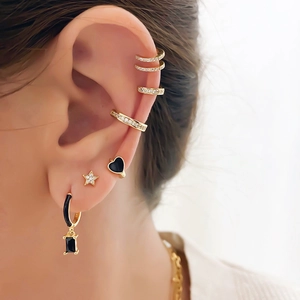 Macro view of gold ear cuff set with heart studs and black pendant hoops for women