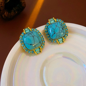 Detail of vintage gold square earrings with turquoise stones and blue rhinestones