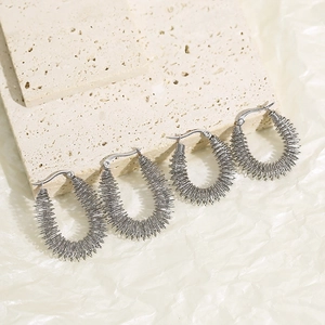 Gros plan sur des boucles d'oreilles argentées à texture nervurée et style industriel