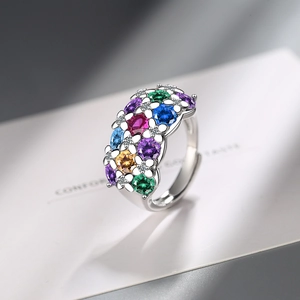 Silver flower ring with colorful gemstones and open band on vintage book page