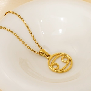 Golden Cancer zodiac pendant necklace in stainless steel on a white ceramic plate