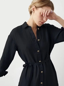 Dettaglio dell'abito a camicia nero con bottoni metallici e cintura in vita abbinata