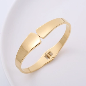 Minimalist golden spring hinge bangle with high-polished 18K gold finish on ceramic plate