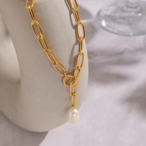 Gros plan détaillé d'un collier chaîne trombone dorée avec pendentif perle naturelle