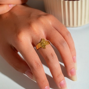 Close-up of golden butterfly ring on finger showing hollow 18K steel craftsmanship