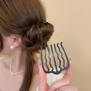 Détail d'un peigne à cheveux noir ondulé pour fixer les chignons et les mèches rebelles