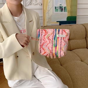 Close-up of pink knit makeup bag with colorful wave patterns held by a model