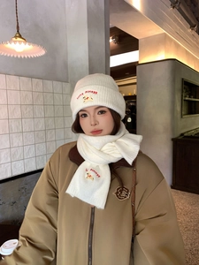 Detail of white knit beanie and scarf set featuring red lucky puppy embroidery