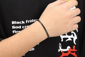 Detailed close-up of a masculine black stainless steel chain bracelet worn on a wrist