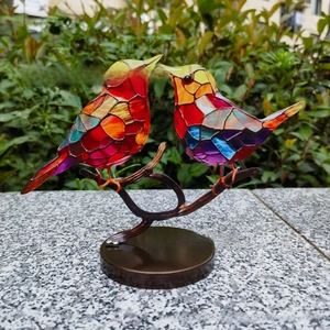 Detailed view of colorful glass birds mosaic art on a branch stand for home decor