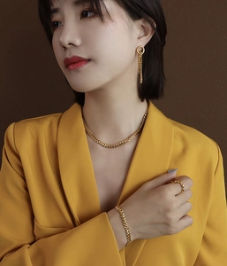 Close-up of golden leaf jewelry set including herringbone chain and tassel earrings