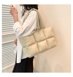 Detail of light khaki quilted puffer tote showing soft padded texture and wide shoulder strap