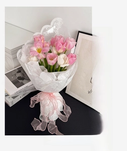Close-up of white floral lace wrap and pink wavy ribbon on a tulip bouquet