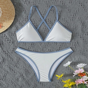 Flat lay of a white bikini set with blue contrast trim on a dark knit textured surface
