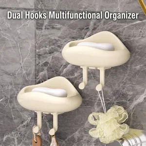 Two cloud-shaped cream soap holders with hooks on a marble wall in a bathroom