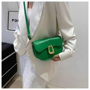 Detail of green leather saddle bag with gold metal buckle on a fashion model