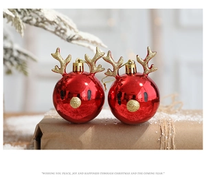 Close-up of red glossy reindeer Christmas ball ornaments with gold glitter antlers on a gift box